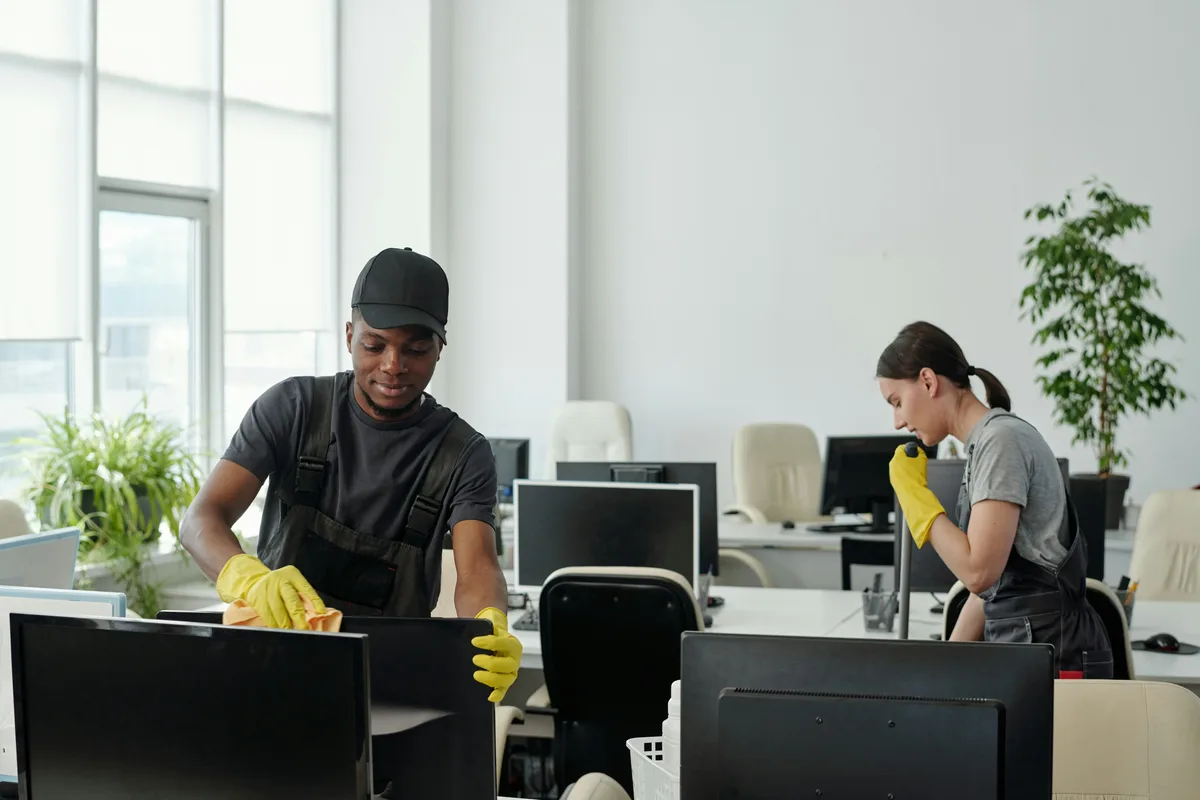 Two people wiping office workstations with protective gloves