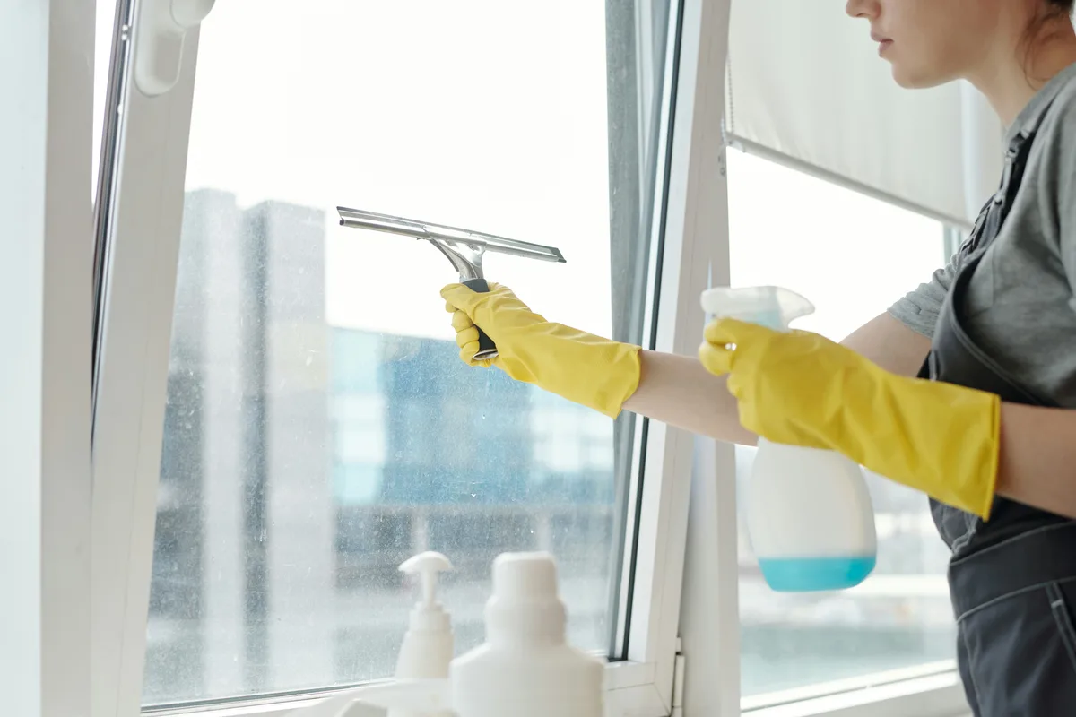 Two people cleaning interior windows in an office