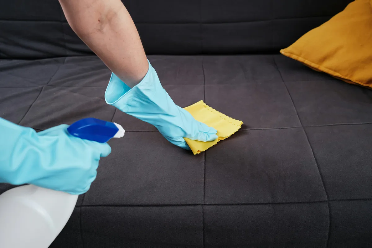Gloved hands and a cloth beside seating