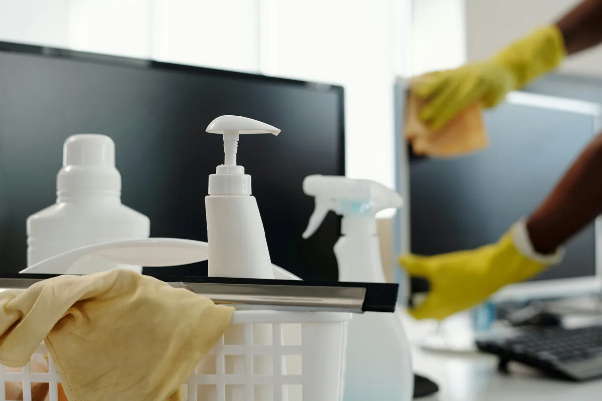 Cleaning products and cloths beside an office workstation
