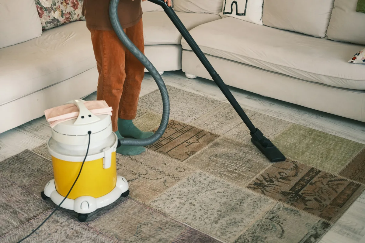Person vacuuming a rug in a home