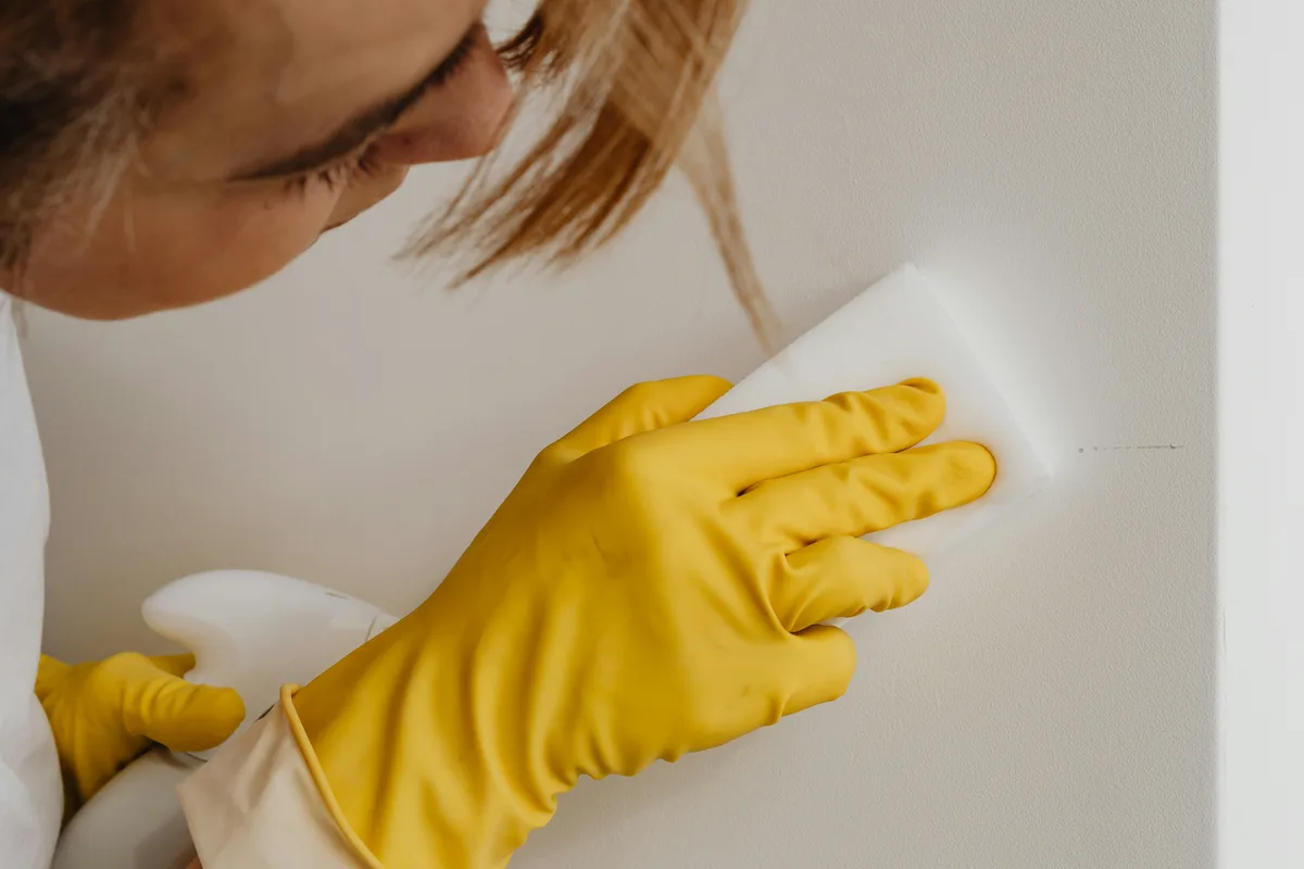 Person wiping a wall with a yellow cleaning cloth